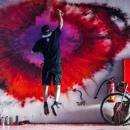 man jumping while painting graffiti on a wall